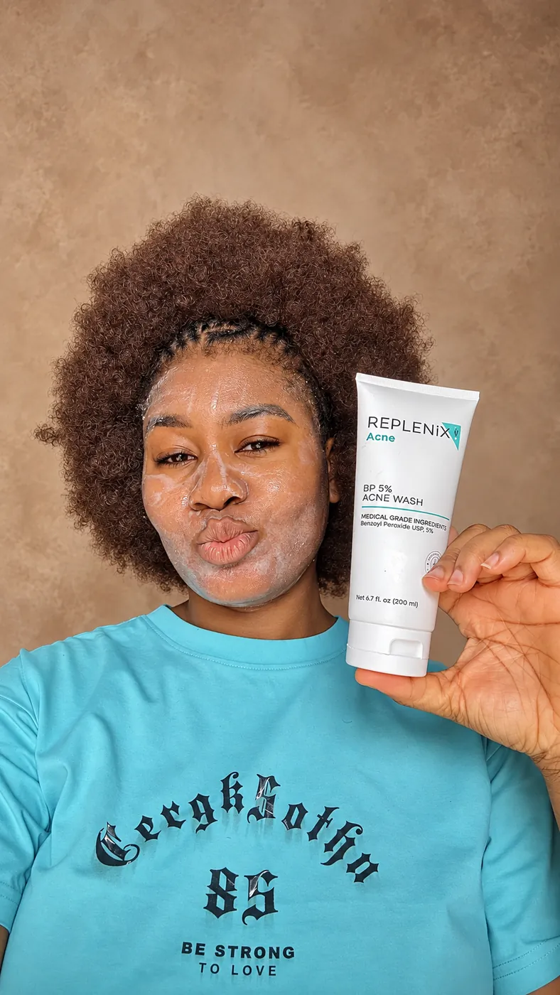 Cynthia holding a cleanser beside her freshly washed face
