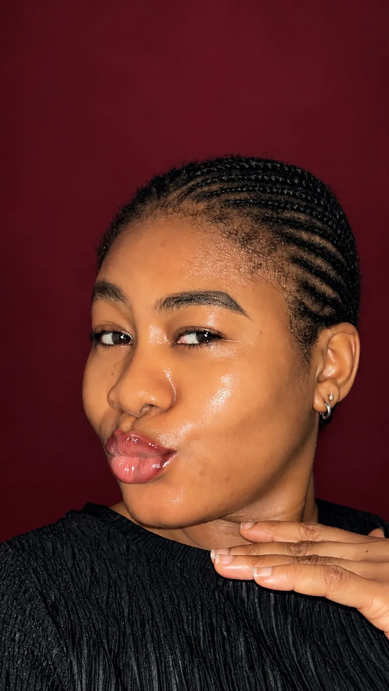 Close portrait of Cynthia showing her glowing skin against a burgundy studio background