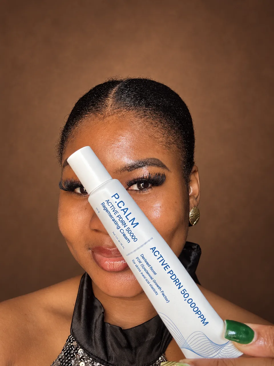 Cynthia holding a P Calm retinoid cream directly toward the camera