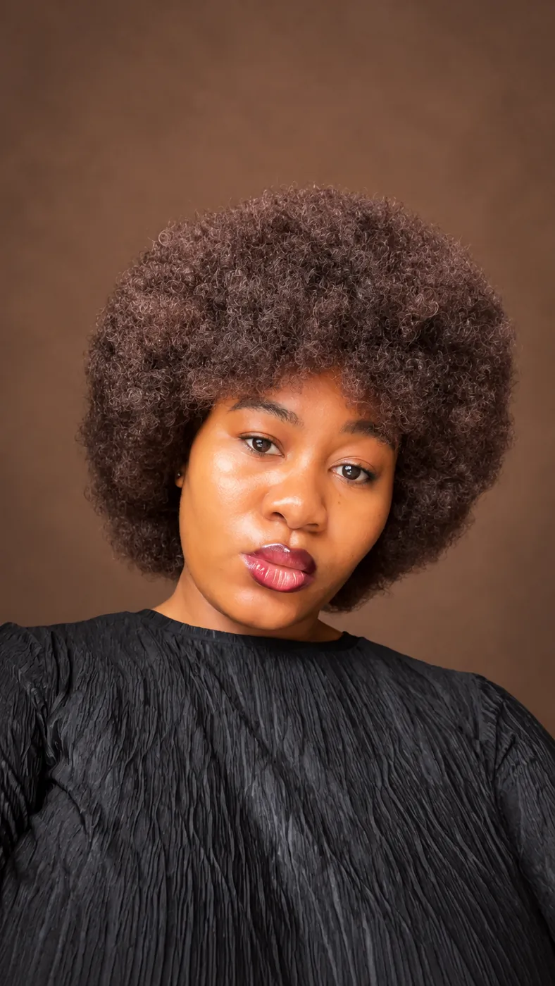 Close portrait of Cynthia with her natural afro against a cocoa studio background